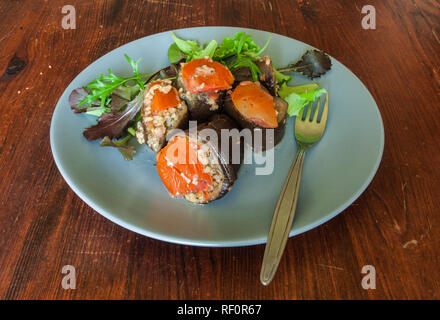 Piastra di colore blu sulla tavola di legno con le melanzane farcite con riso e verdure, luce naturale. Foto Stock