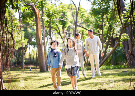 Famiglia asiatica con due bambini passeggiate rilassanti divertirsi nel parco felice e sorridente. Foto Stock