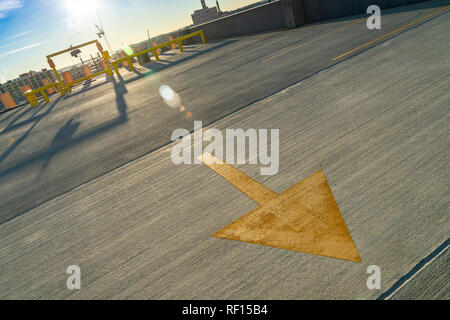 Una freccia gialla in vuoto parcheggio Foto Stock