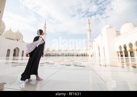 Tradizionalmente condita arabo donna vestita di nero burka wisiting Sheikh Zayed Grande Moschea di Abu Dhabi, negli Emirati Arabi Uniti. Foto Stock