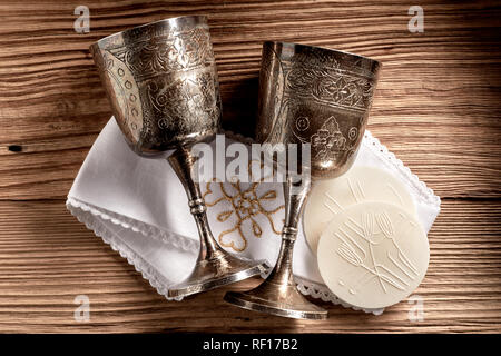 Hostie wafer con argento bicchieri a calice e il panno pronto per la Santa Comunione di servizio in una chiesa in legno rustico sfondo Foto Stock