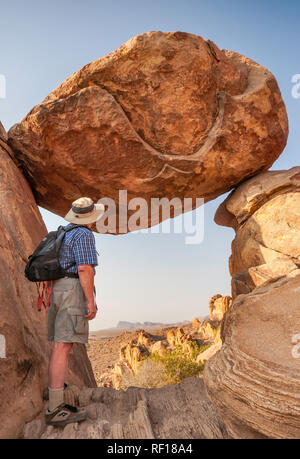 Escursionista a Balanced Rock, noto anche come The Window, al Grapevine Hills Trail, ai Chisos Mountains in lontananza, nel Big Bend National Park, Texas, Stati Uniti Foto Stock