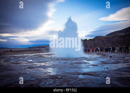 I turisti sono guardando l eruzione del Strokkur geyser, che è parte dell'Haukadalur area geotermica e uno dei più famosi geyser in Islanda. Foto Stock