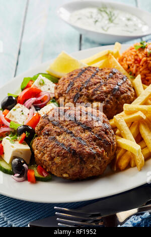 Bifteki piccante, frikadelle o frikkadel polpette con la carne macinata e di agnello servito con insalata greca e patatine fritte Foto Stock