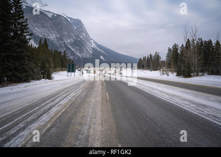 Vista di un gelido strada innevata in Banff Alberta Canada, conduce la Trans-Canada Highway con le Montagne Rocciose Canadesi in background Foto Stock