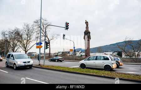 TRIER, Germania - Feb 21, 2015: vetture tedesche e la statua dell'Imperatore Costantino tenendo una corona con una croce in cima ad una colonna ai piedi della Kaiserstrasse strada imperiale sul fiume Moselle Foto Stock