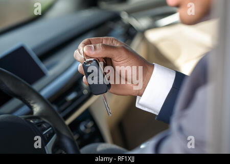 Giovane uomo seduto all'interno dell'auto con chiave cllose-up Foto Stock