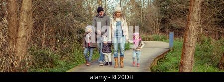La famiglia felice camminando insieme tenendo le mani nella foresta Foto Stock