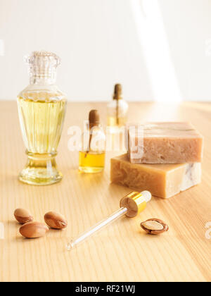 Bottiglie con cosmetici argan olio dadi. Mezzi di cosmetici. Prodotto alimentare. Vaso con olio di argan e sapone artigianale sullo sfondo di legno. Foto Stock