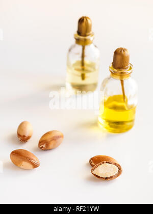 Bottiglie con olio di argan dadi. Mezzi di cosmetici. Prodotto alimentare. Vaso con olio di argan sullo sfondo isolato. Foto Stock