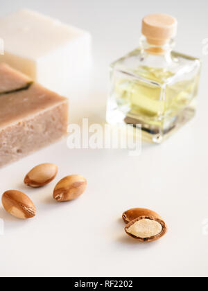 Bottiglie con olio di argan dadi. Mezzi di cosmetici. Prodotto alimentare. Vaso con olio di argan e sapone artigianale sullo sfondo isolato. Foto Stock