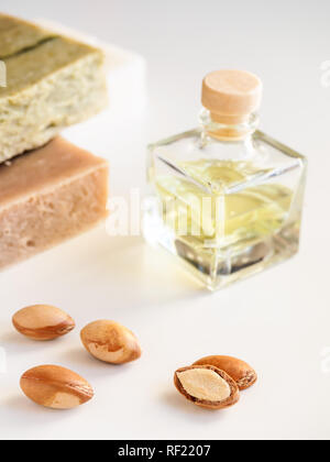 Bottiglie con il prezioso olio di argan dadi. Mezzi di cosmetici. Prodotto alimentare. Vaso con olio di argan e sapone artigianale sullo sfondo isolato. Foto Stock