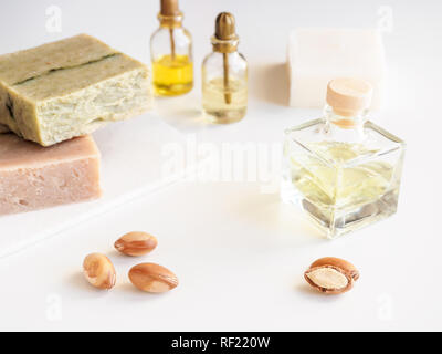 Bottiglie con olio di argan dadi. Mezzi di cosmetici. Prodotto alimentare. Vaso con olio di argan e sapone artigianale sullo sfondo isolato. Foto Stock