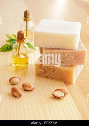 Bottiglie con cosmetici argan olio dadi. Mezzi di cosmetici. Prodotto alimentare. Vaso con olio di argan e sapone artigianale sullo sfondo di legno. Foto Stock