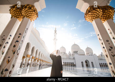 Tradizionalmente condita arabo donna vestita di nero burka wisiting Sheikh Zayed Grande Moschea di Abu Dhabi, negli Emirati Arabi Uniti. Foto Stock