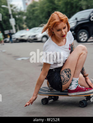 Giovane donna cavallo su carver skateboard su una strada Foto Stock