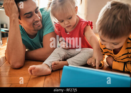 Il padre e i suoi figli con tavoletta digitale in casa Foto Stock