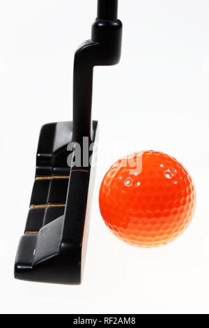 Arancio brillante pallina da golf accanto alla testa del putter nero Foto Stock