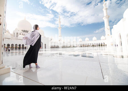 Tradizionalmente condita arabo donna vestita di nero burka wisiting Sheikh Zayed Grande Moschea di Abu Dhabi, negli Emirati Arabi Uniti. Foto Stock