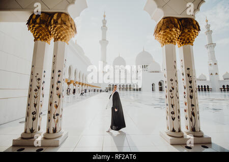 Tradizionalmente condita arabo donna vestita di nero burka wisiting Sheikh Zayed Grande Moschea di Abu Dhabi, negli Emirati Arabi Uniti. Foto Stock