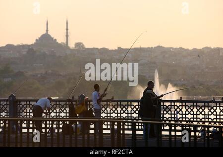 I pescatori sul Ponte di Galata spanning the Golden Horn, un edificio a due piani ponte con una strada sopra e bar e ristoranti al di sotto di Foto Stock