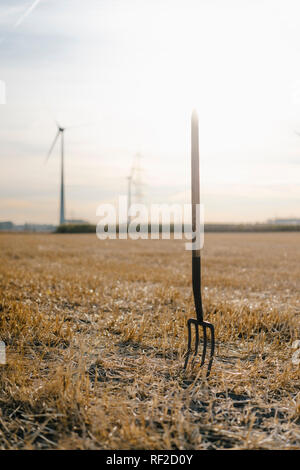 Forcone in campo nel paesaggio rurale con le turbine eoliche in background Foto Stock