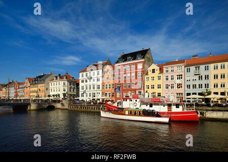 Barche sul canal di fronte casa colorate facciate, il quartiere del divertimento, Nyhavn, Copenhagen, Danimarca Foto Stock