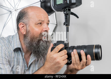 Una immagine di un barbuto Fotografo senior al lavoro Foto Stock