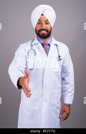 Indian Sikh medico uomo sorridente e dando handshake Foto Stock