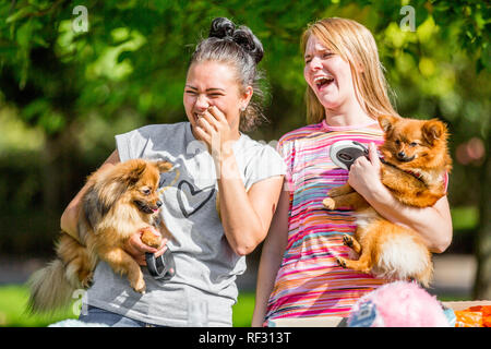 Due ragazze di ridere con i loro cani nel parco di un dog show Foto Stock