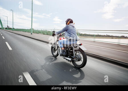 Giovane donna riding motociclo sul ponte Foto Stock