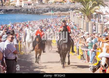 Cavalli e Cavalieri lasciando La Enramada beach dopo la balneazione i loro animali in mare a San Sebastian romeria, fieasta, La Caleta, Tenerife, può Foto Stock