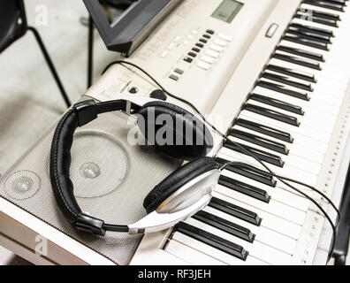 Le cuffie sono in appoggio sui diffusori di un pianoforte elettrico. Foto Stock