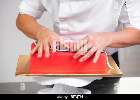 Professional pasticcere rendendo la deliziosa torta di rosso, close up . Foto Stock