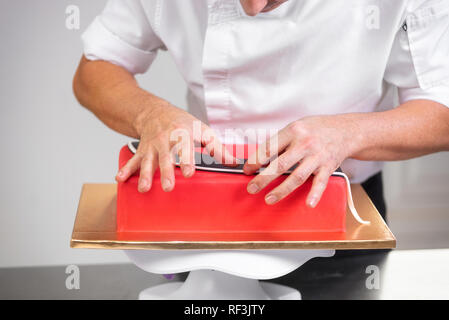 Professional pasticcere rendendo la deliziosa torta di rosso, close up . Foto Stock