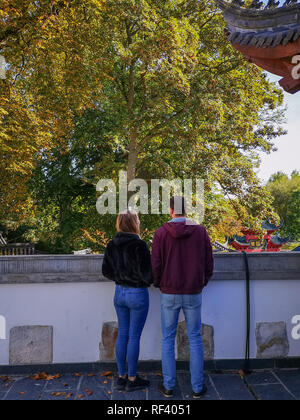 Settembre 2018 - Hainaut, Belgio: Caucasian coppia giovane godendo della vista sulla tradizionale semiscafi giardino in Wildlife Park Pairi Daiza Foto Stock