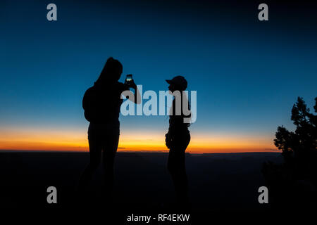 Donna di scattare una foto di un amico su un telefono mobile (cellulare), tramonto a Hopi Point, il Parco Nazionale del Grand Canyon, AZ, Stati Uniti d'America, Foto Stock