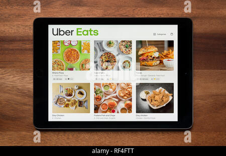 Il sito web di Uber mangia è visto su un tablet iPad, il quale è appoggiato su un tavolo di legno (solo uso editoriale). Foto Stock