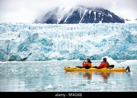 SVALBARD, Norvegia — i turisti in kayak esplorano le acque ghiacciate e i paesaggi incontaminati della regione artica che circonda Svalbard. Questa forma unica e avventurosa di turismo offre un'esperienza ravvicinata con l'ambiente artico, mostrando la bellezza mozzafiato della regione e i fragili ecosistemi. Foto Stock