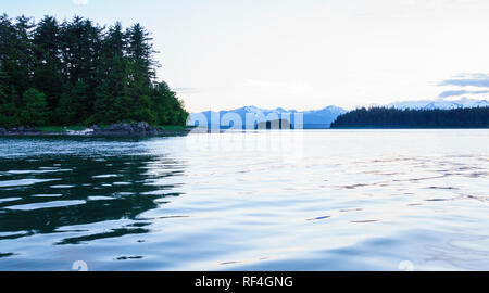 Isole boschive, montagne innevate e acqua al crepuscolo in Auke Bay nei pressi di Juneau, in Alaska. Bellissima, tranquilla e serena scene naturali. Foto Stock