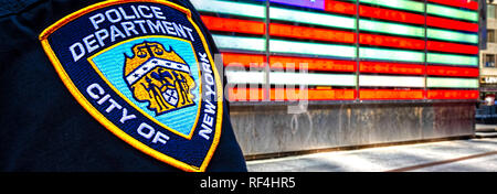 A New York City funzionario di polizia in piedi in Time Square illuminata di una bandiera americana segno.