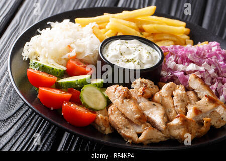 Appena cucinata piastra shawarma con pollo, patatine fritte, verdure e salsa di close-up su una tavola di legno orizzontale. Foto Stock