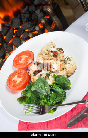 Cavolfiore arrosto di manzo servita con Spinaci appassito e pomodoro grigliate Foto Stock