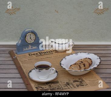 Tè inglese di fronte ad un blu pallido Wedgwood Jasperware guarda con applicata la piastra di sfiato di argilla bianca su un vecchio quotidiano tedesco Der Patriot Foto Stock