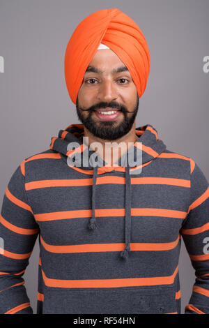 Bel giovane sikh indiana uomo che indossa turban arancione Foto Stock