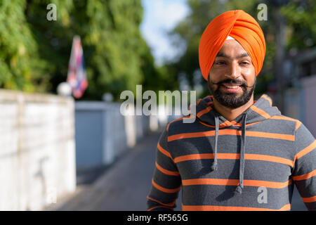 Indiano uomo Sikh indossando turbante nelle strade all'aperto mentre sorridente Foto Stock