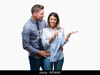 I giovani lavoratori azienda giovane su sfondo isolato stupiti e sorridente alla fotocamera durante la presentazione con la mano e puntando con il dito. Foto Stock