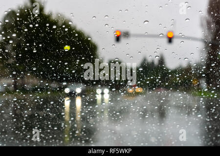 Cars driving attraverso la pioggia; le gocce di pioggia sul parabrezza Foto Stock
