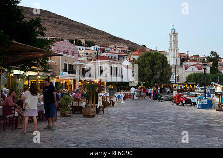 Halki Island, Grecia - 27 agosto 2018. La gente a piedi sul lungomare pieno di ristoranti tradizionali taverne greche. Halki è il più piccolo Foto Stock