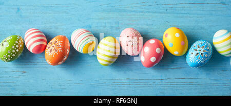 Fila di colorfully dipinto di uova di Pasqua in blu su sfondo di legno, grandangolo immagine. Foto Stock